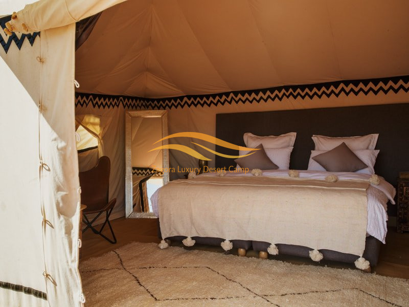 Luxury desert tent bedroom interior at Zagora Desert Camp with king size bed and Moroccan decor